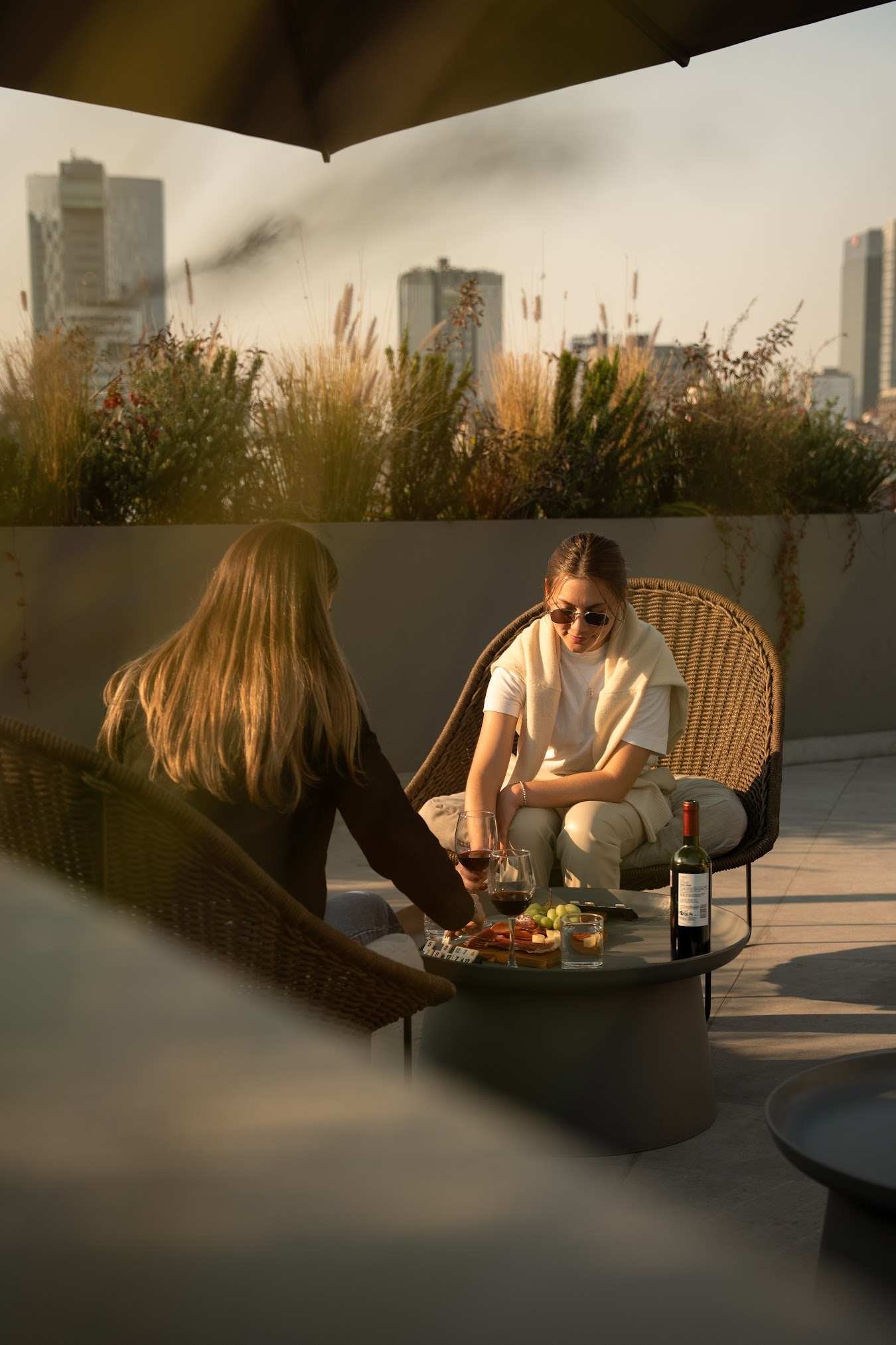 Friends sharing wine on the rooftop with the skyline behind